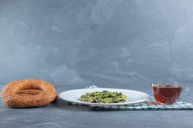 Cup of tea, two bagels and a platter of cooked bean pulses mixed with scrambled eggs on marble table.