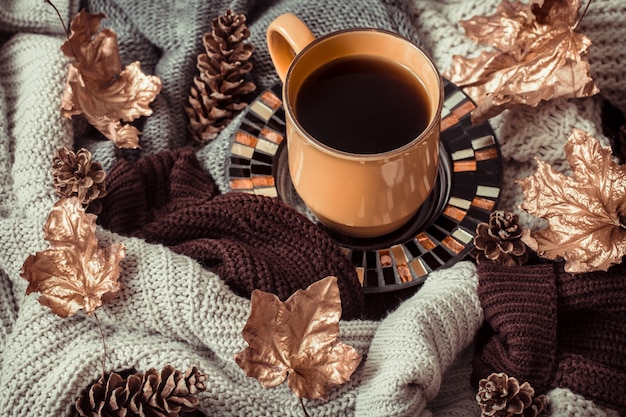 Cup of tea with autumn leaves and sweater