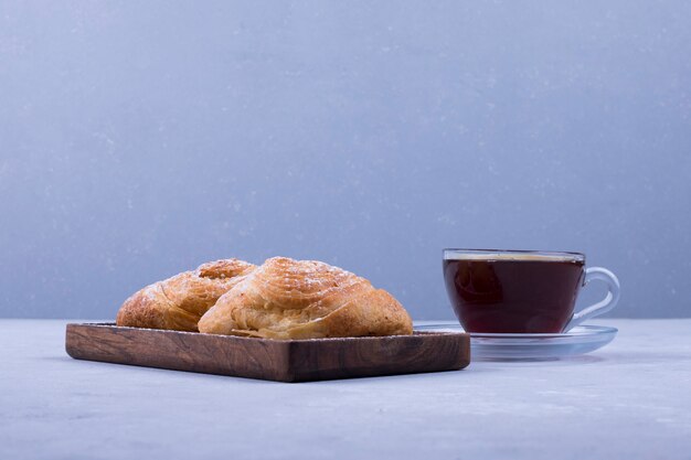 A cup of tea with badamburas in plate on white wooden background