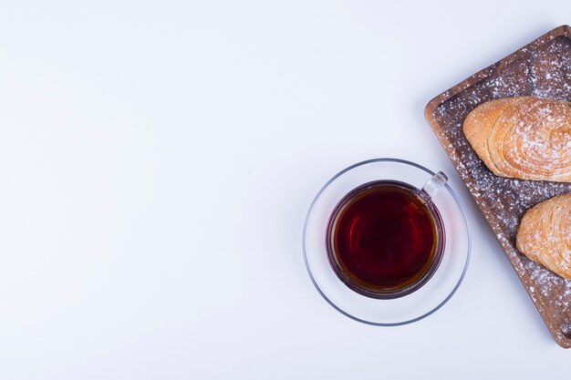 A cup of tea with badamburas in plate on white wooden background