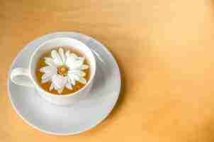 Free photo cup of tea with chamomile flower on a wooden background copy space