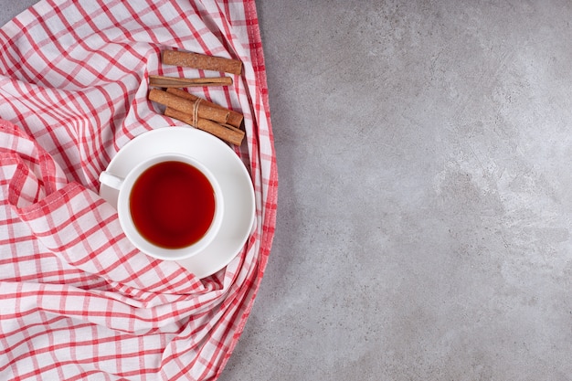 テーブルクロスにシナモンスティックとお茶のカップ