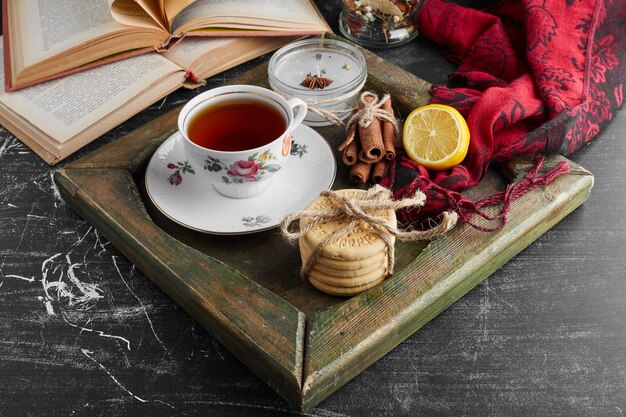 A cup of tea with cookies and fruits. 