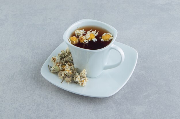 Cup of tea with dried chamomile flowers.  