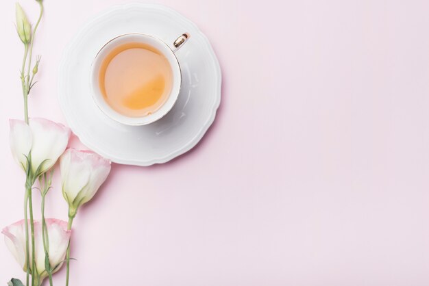 분홍색 배경에 eustoma 꽃과 차 한잔