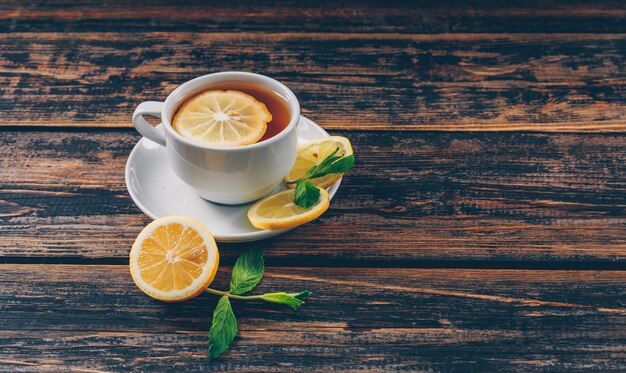 A cup of tea with lemon high angle view on a dark wooden background space for text