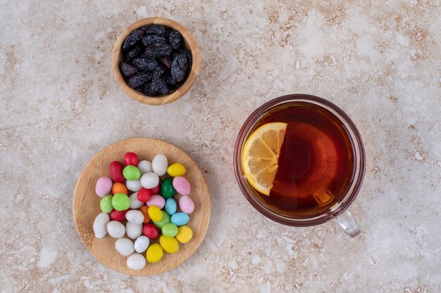 Cup of tea with lemon and plates of sweets on marble surface