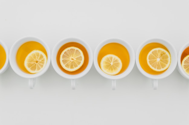 Tazza di tè con i limoni isolati su fondo bianco