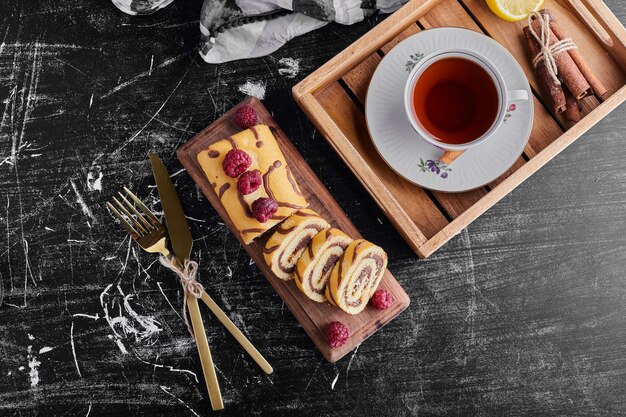 A cup of tea with roll cake, top view. 