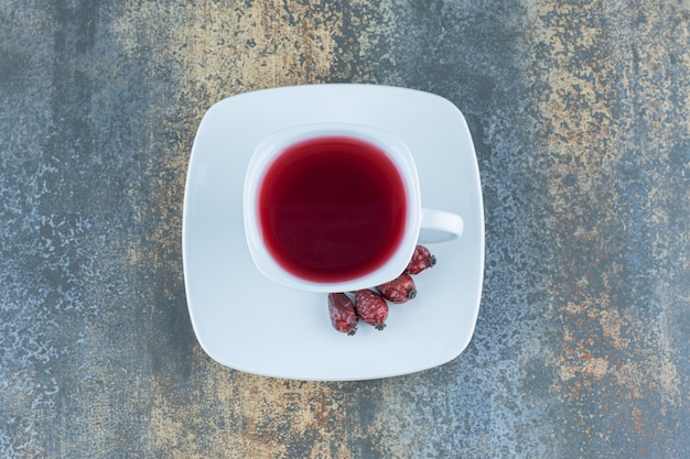 Cup of tea with rosehips on marble.