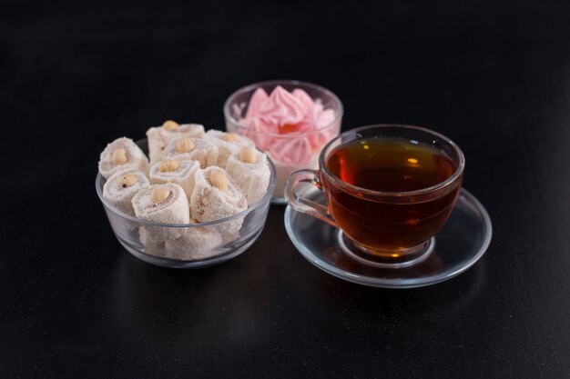 A cup of tea with turkish lokum and marshmallows in the center.