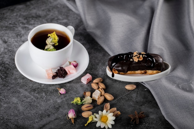 A cup of tea with Turkish lokum, pistachios and chocolate eclair.