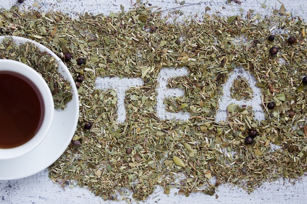 Чашка чая со словом TEA, написанная сухими зеленью