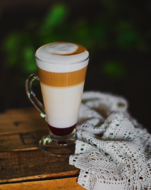 A cup of three layered latte with foam on top