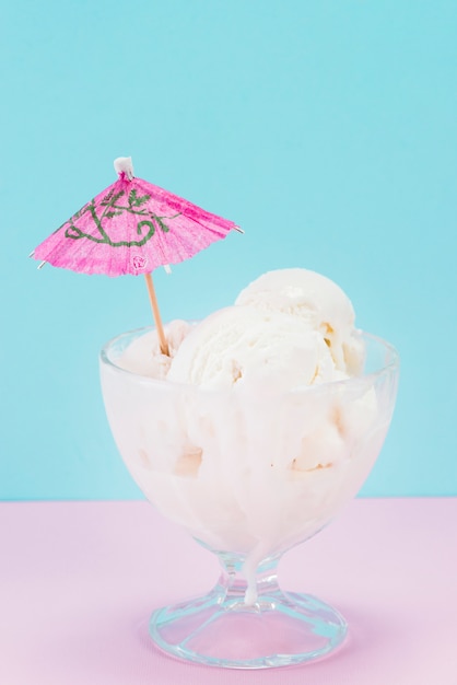 Cup of vanilla ice cream with paper umbrella on top