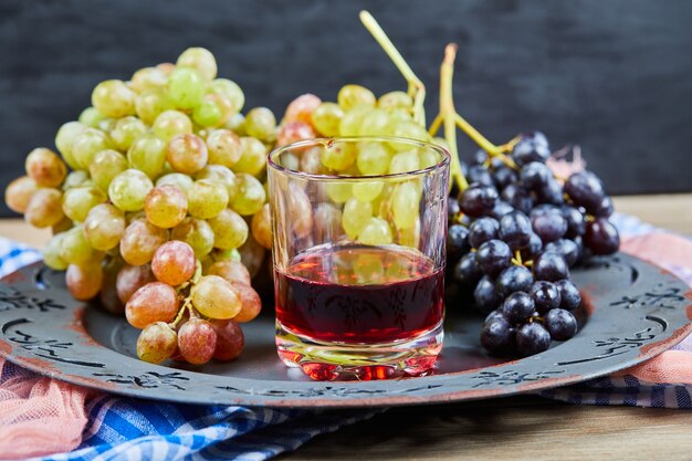 A cup of wine with grape bunches around. 