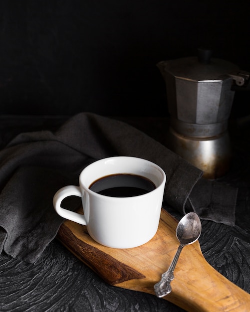 Cup with black coffee on wooden board