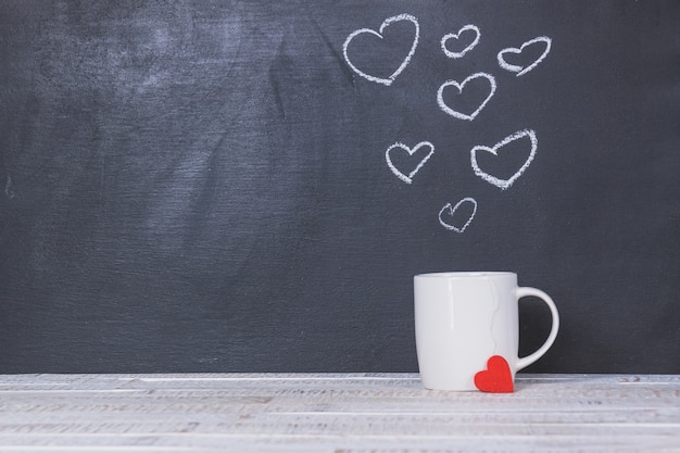 Cup with a blackboard behind with drawn hearts