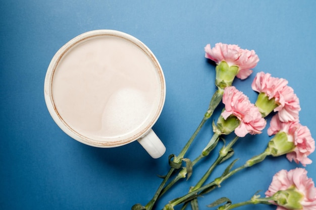 無料写真 青いテーブルの上のコーヒーとピンクのカーネーションの花とカップ