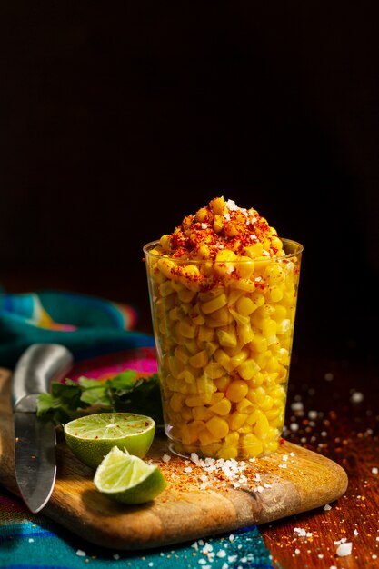 Cup with delicious esquites on wooden board