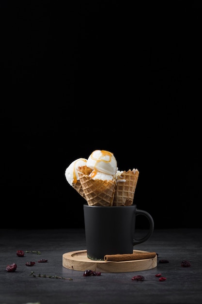 Cup with ice cream on cones on wooden tray