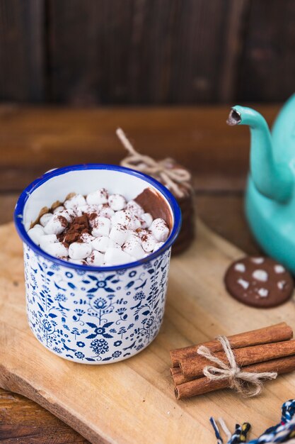 Cup with marshmallow near biscuits and cinnamon