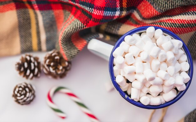 Cup with marshmallow near candy cane and snags