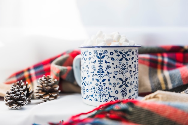 Cup with marshmallow near scarf