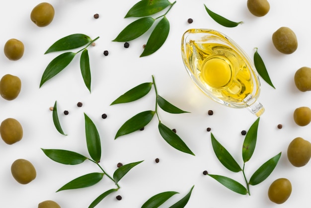 Cup with olive oil surrounded by leaves and olives