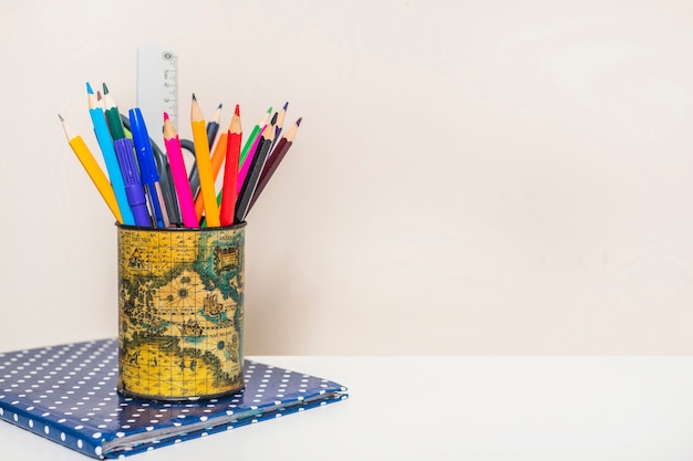 Cup with pencils on notebook