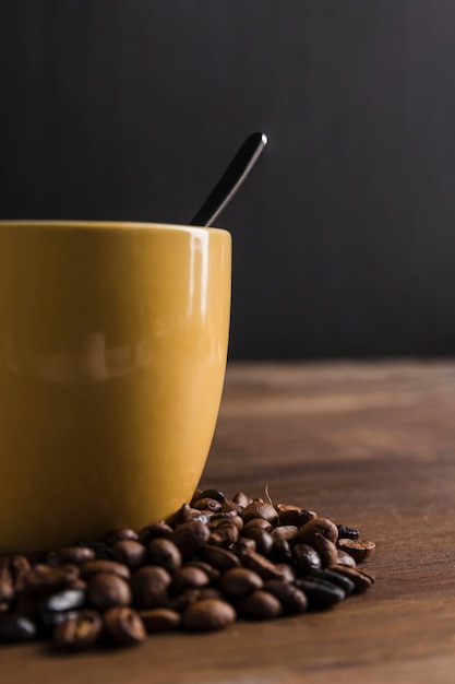 Cup with spoon near coffee beans