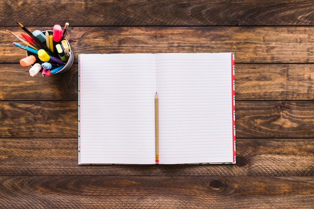 Cup with writing supplies near notepad