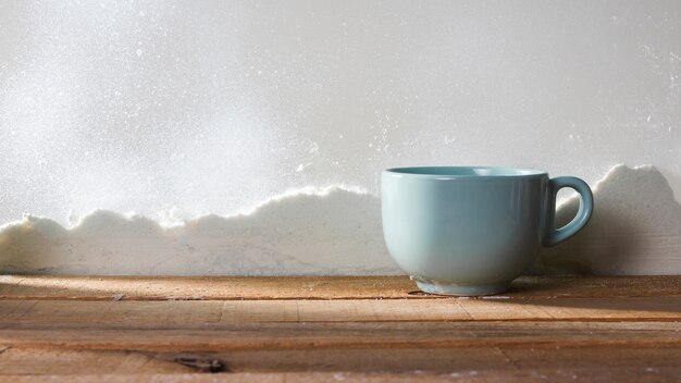 Cup on wood table near bank of snow and snowflakes