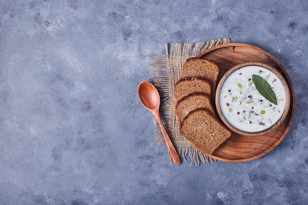 A cup of yogurt soup served with bread slices.