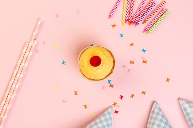 Free photo cupcake and birthday decorations on a pink background