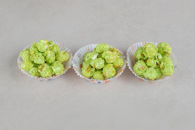 Cupcake casi riempiti con porzioni di popcorn aromatizzati sul tavolo di marmo.