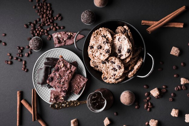 Кекс; печенье и шоколадные трюфели из кофейных зерен и шоколада на черном фоне