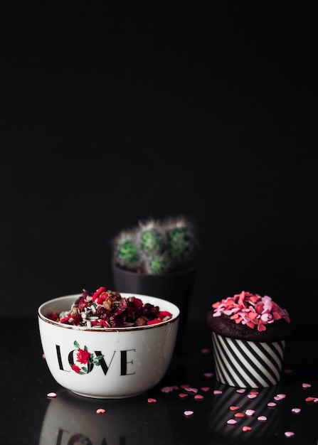 Free photo cupcake and dry fruits in the bowl on black background