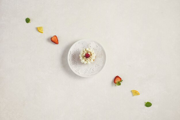 Cupcake on a plate surrounded by a line of fruits