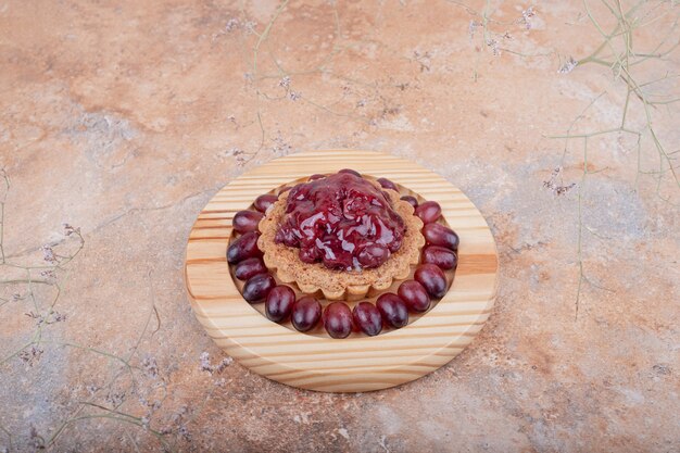 A cupcake or tartalette with cornel sauce on top and cornel berries around.