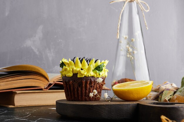 Free photo a cupcake with sunflower decoration and lemon.