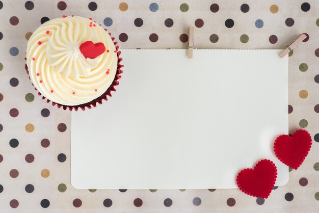 Кекс с двумя красными сердцами над пустой бумагой
