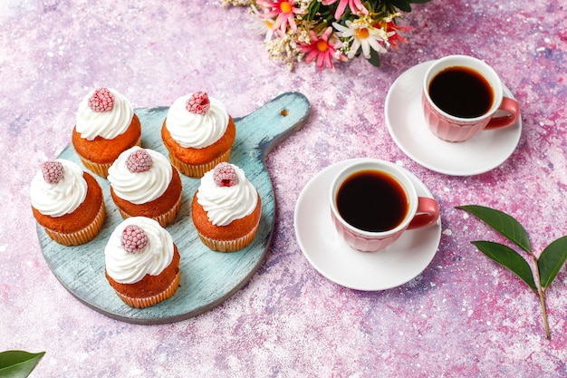 Cupcakes decorated whipped cream and frozen raspberries.