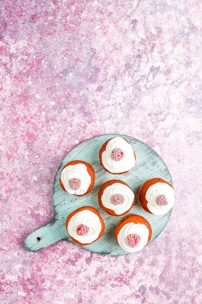 Free photo cupcakes decorated whipped cream and frozen raspberries.