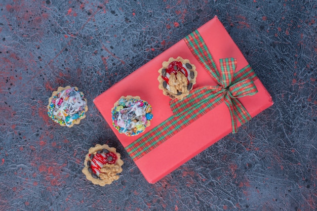 Кексы и подарочный пакет на абстрактном столе.