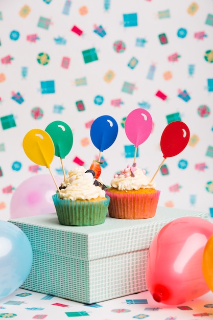 Cupcakes with bright balloon toppers on box