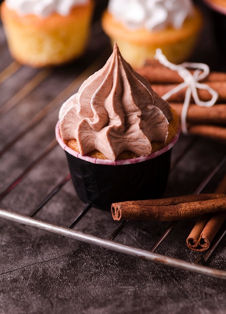 Free photo cupcakes with icing and cinnamon sticks