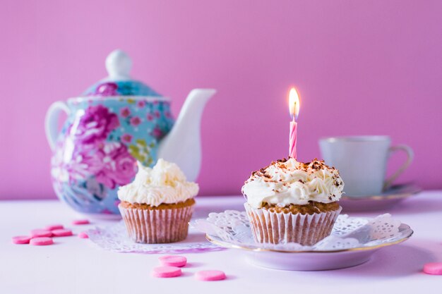 Cupcakes with illuminated candle on table top