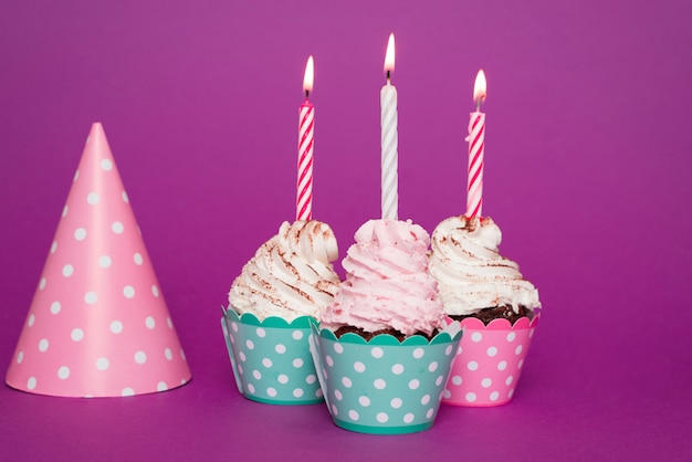 Cupcakes with lit candle next to hat