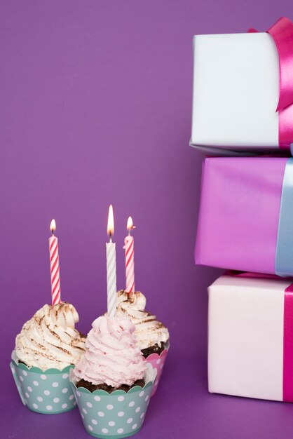 Cupcakes with lit candle next to presents